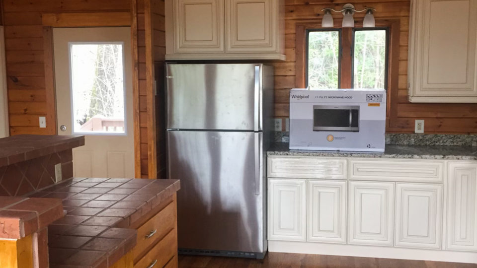 Mountain Cabin Kitchen with White Cabinets and Stainless Fridge.